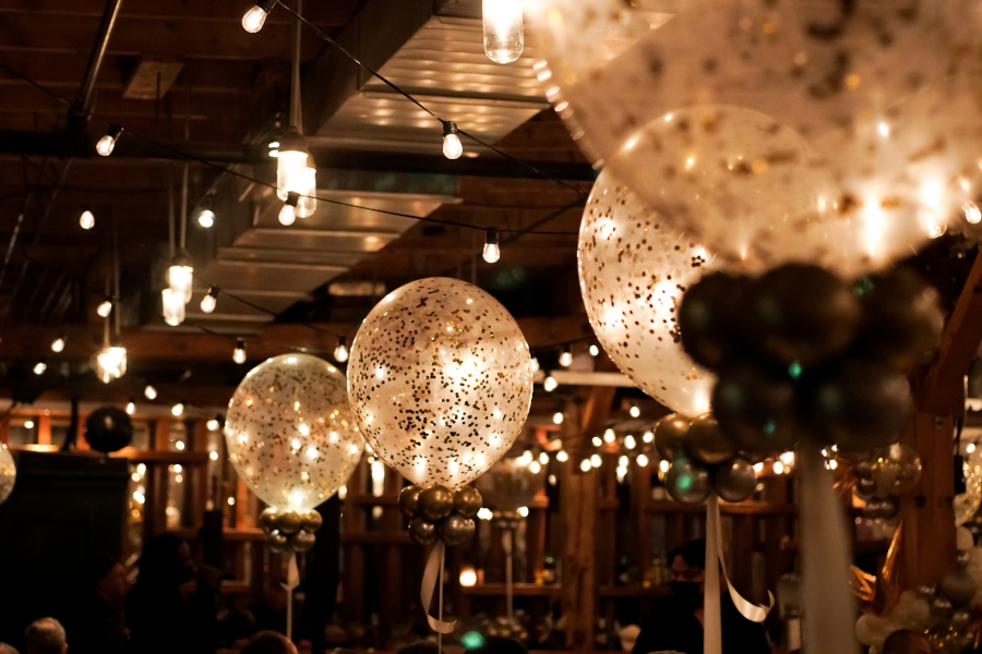 Glitter-filled balloons in a 19th-century carpentry shop with high pine ceilings and atmospheric lighting