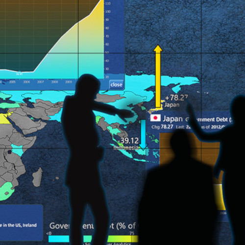 Silhouette of a person interacting with a multi-touch wall to inspect Government Debt comparison between Japan and Indonesia.